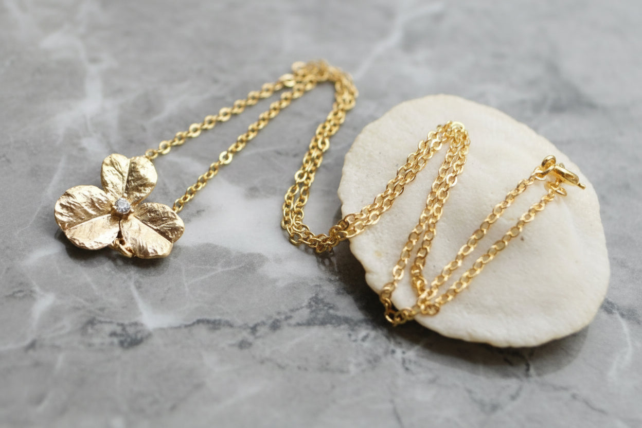 Gold necklace with a floral pendant on a gray surface