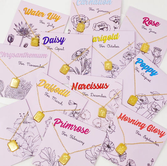 A collection of birth month flower pendant necklaces with gold-colored pendants and chain, each labeled with the corresponding month and flower name.