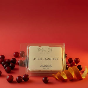 Spiced Cranberry wax melt in packaging with cranberries on a red background