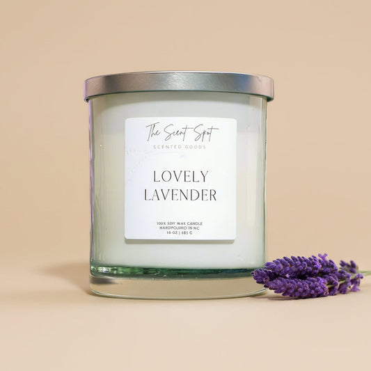 Candle labeled 'Lovely Lavender' on a surface with lavender flowers in the background